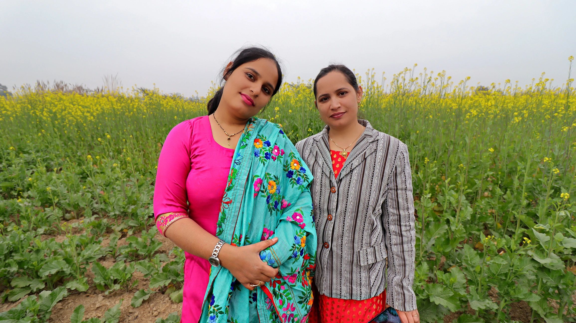 Indian women farmers standing together near a mustard crop field