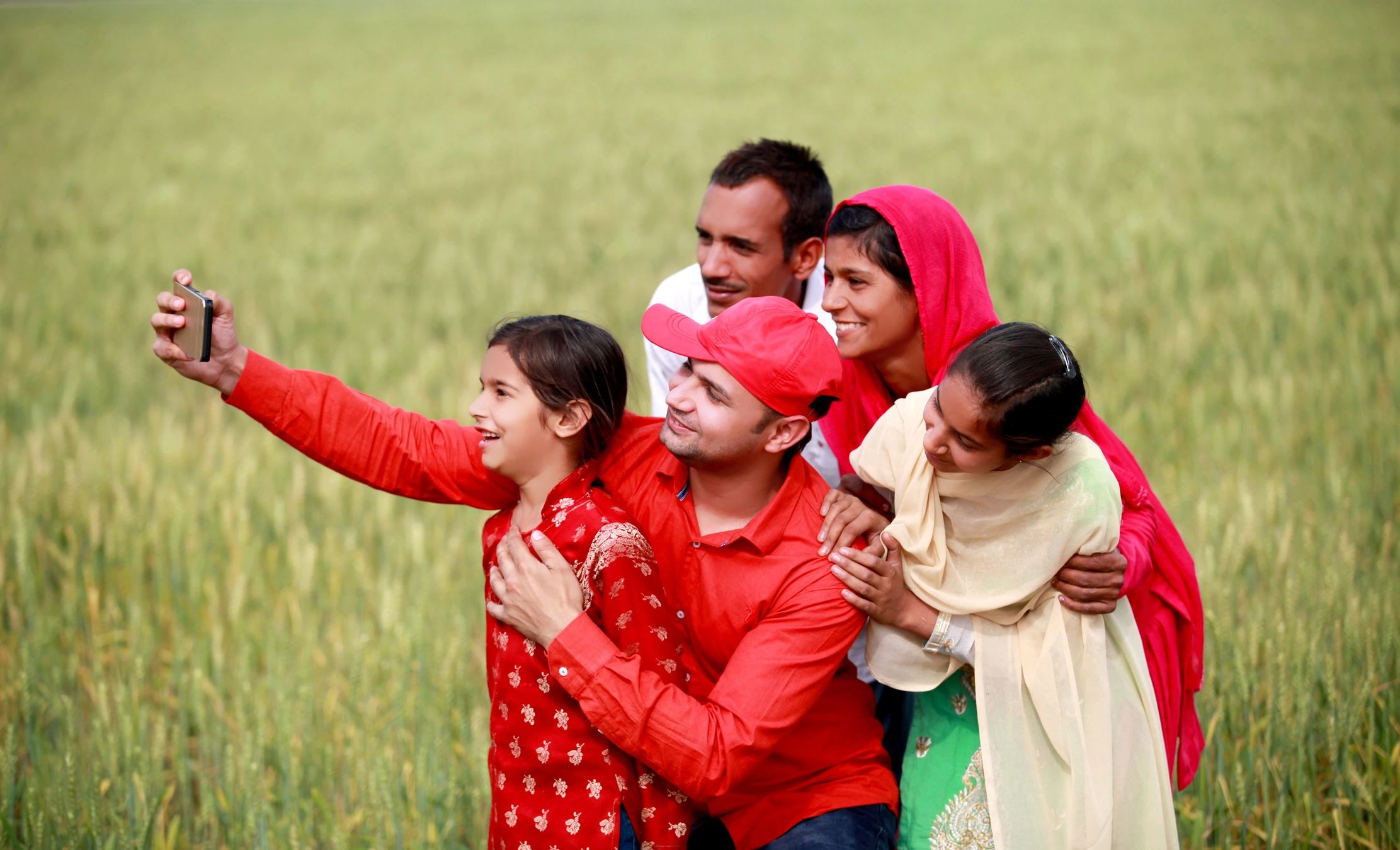 Cheerful Indian family outdoors near a green field