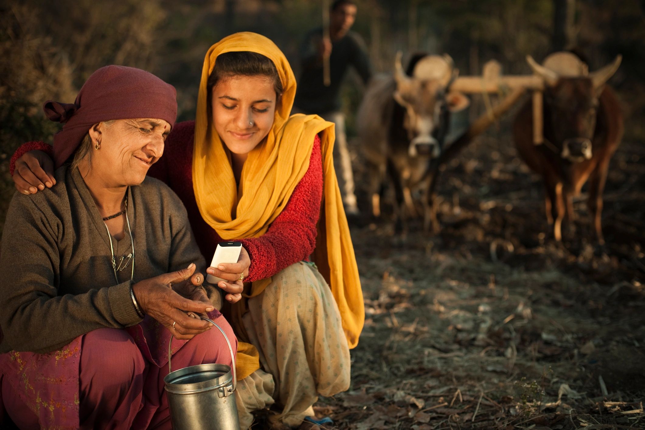 Rural Indian family using a mobile phone near agricultural land